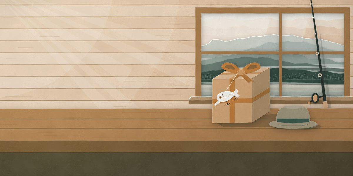 Paper-cut gift box in kraft paper with copper ribbon beside a fishing rod in a cabin